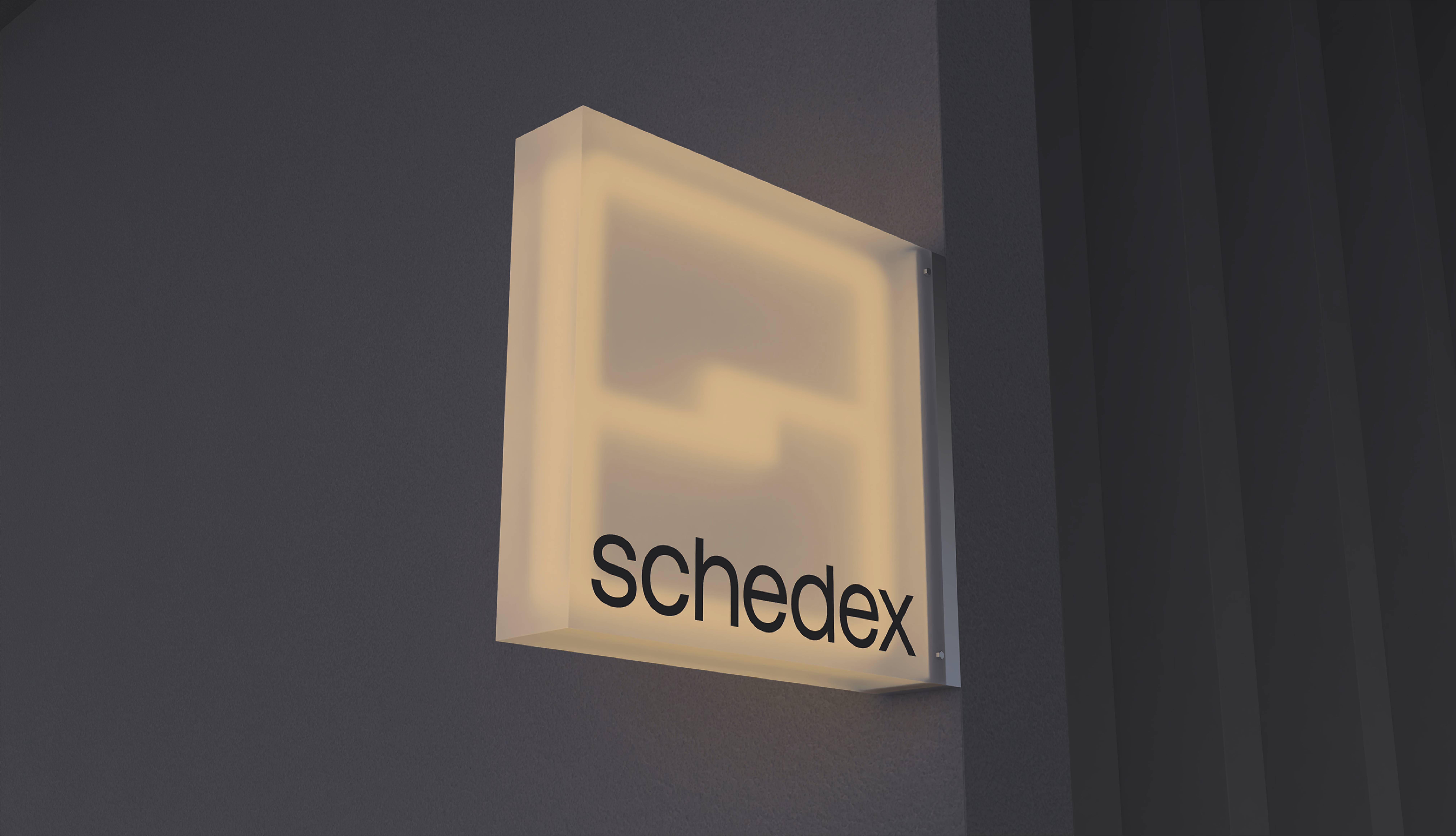 暗い壁に灯る schedex のロゴサイン